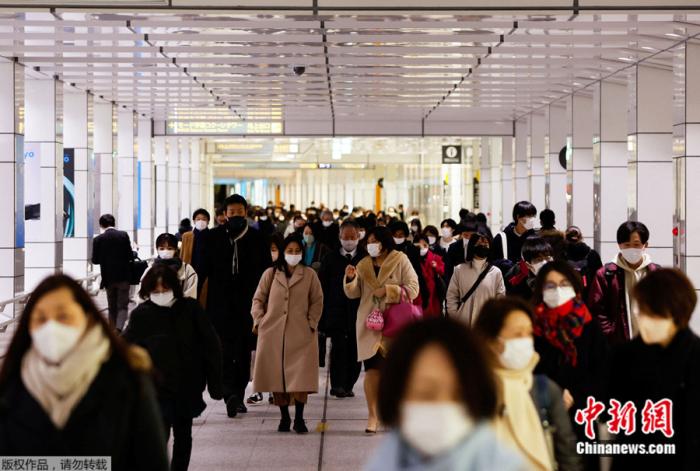 日本民众戴着口罩走过东京一座火车站的大厅