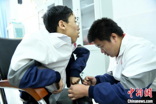 江西省南康中学北校区的高三学生朱金祥(右)正在给钟华强(左)系好鞋带。 卓忠伟 摄