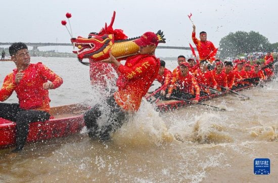 6月22日，在湖南省岳阳市湘阴县湘江临资口水域，参加龙舟赛的队员接“龙头”下水。