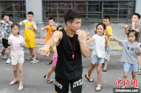 图为大学生志愿者在组织孩子们参加体育健身活动。廖光福 摄