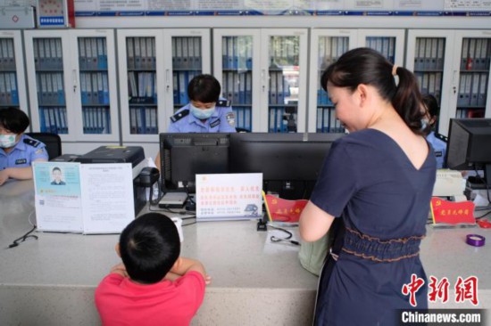 图为一名家长正在办证窗口前为孩子申领居民身份证。刘俊聪 摄
