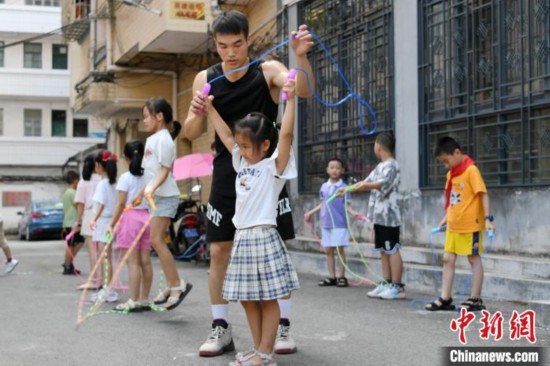 图为大学生志愿者在教孩子们学跳绳。廖光福 摄