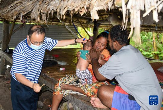 7月21日，中国海军“和平方舟”号医院船医生在基里巴斯一民众家为一名幼儿处理头部皮肤感染。新华社记者 黎云 摄
