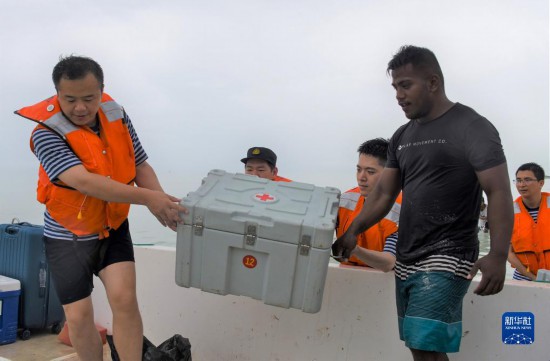 7月21日，中国海军“和平方舟”号医院船医护人员携带医疗设备和药品，乘渔船前往基里巴斯一小岛为民众提供医疗服务。新华社记者 黎云 摄
