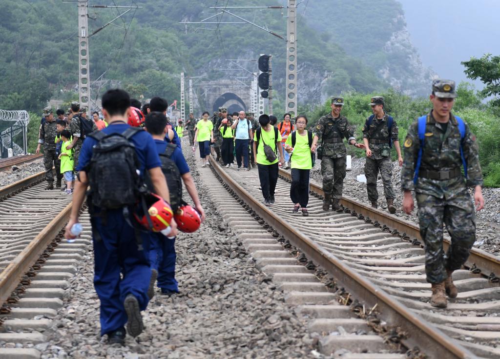 8月2日，部分滞留在北京市门头沟山区受困列车的旅客，在救援人员帮助下前往转运客车。新华社记者张晨霖 摄