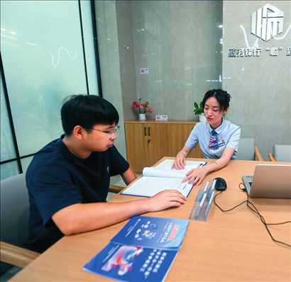 在杭州市临安区政务服务中心的“为企服务中心”，党员志愿者（右）解答企业主的疑问（2023年7月7日摄）。徐昱摄/本刊