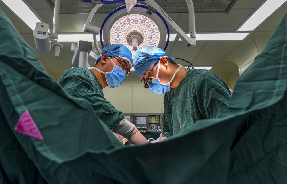 在新疆喀什地区第二人民医院手术室，上海援疆医生张俊文（右）和当地医生阿迪力江为患者做二尖瓣置换手术（2018年11月23日摄）。阿迪力江是张俊文负责培养的年轻医生之一。新华社记者 胡虎虎 摄