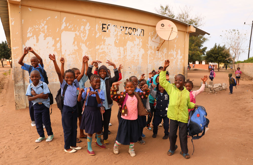 2023年7月25日，莫桑比克马普托省皮科科村学校的孩子们站在装有中国援助的卫星电视接收天线的房屋前。新华社记者 董江辉 摄