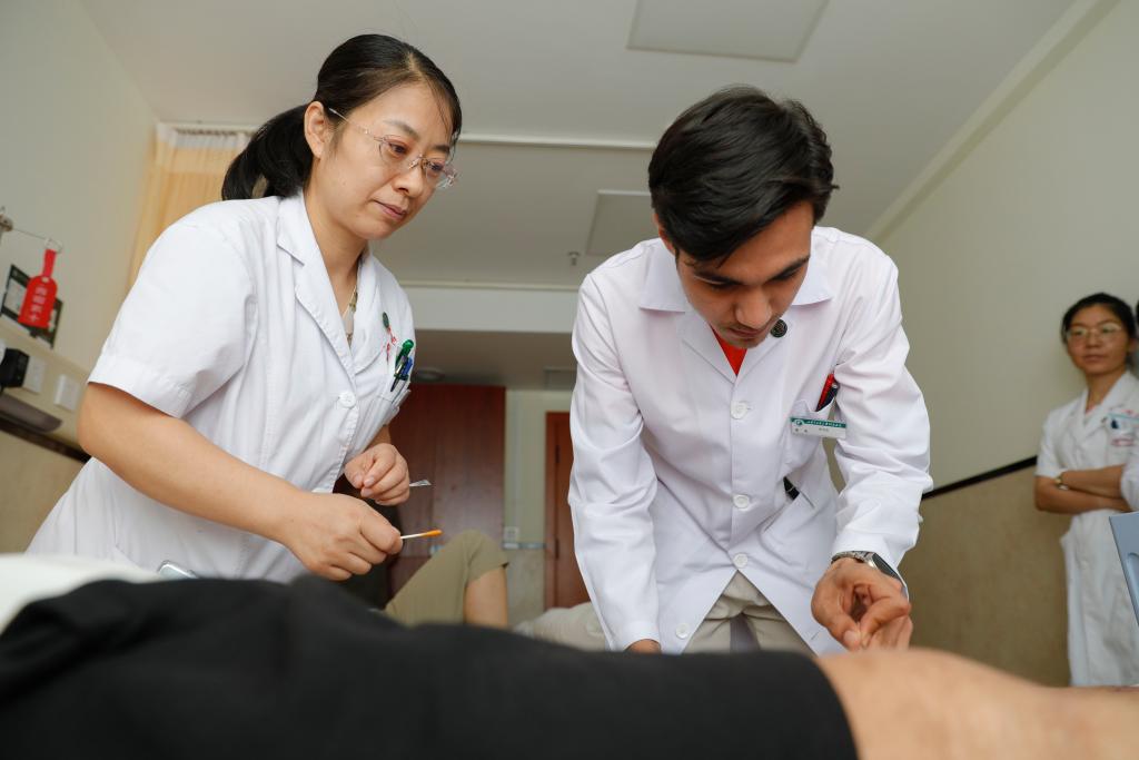 2023年7月28日，甘肃中医药大学针灸推拿专业的土库曼斯坦留学生迪达（右）在老师指导下为患者进行针刺治疗。 新华社记者 陈斌 摄