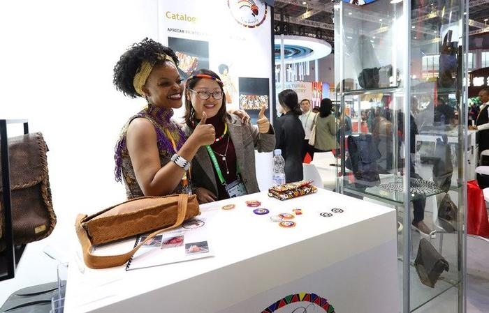 11月6日，一位参观者（右）在第六届进博会国家展南非展台试戴传统首饰。