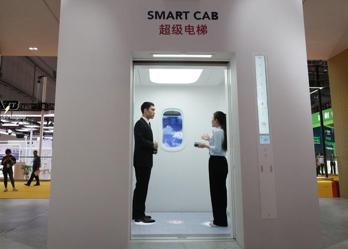 11月5日，工作人员（右）在第六届进博会上向参观者介绍奥的斯公司全新推出的超级电梯。