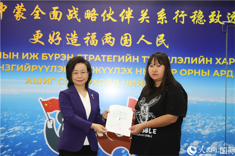 11月10日，沈敏娟大使向蒙古国公民尼亚姆库（右）颁发最后一份领事认证书。人民网记者 霍文摄