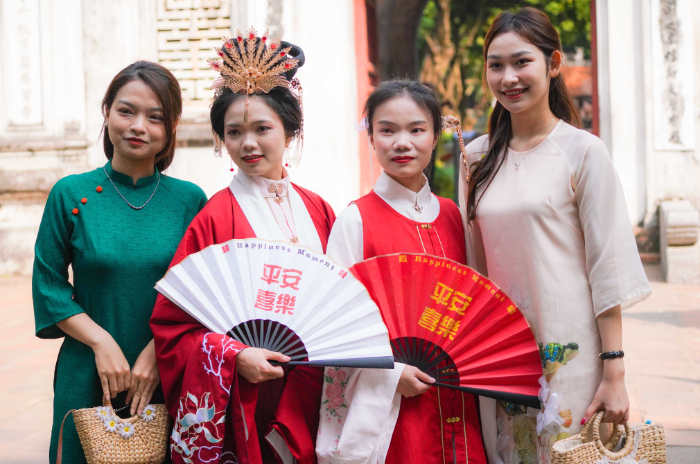 身穿古装的中国游客和身穿越南传统服饰奥黛的越南青年在文庙门前合影。