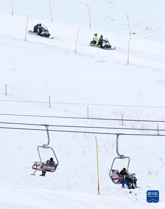 12月21日，游客在那拉提国际滑雪场体验雪上摩托（上）和索道缆车项目。