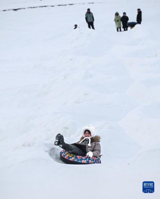12月21日，游客在那拉提国际滑雪场体验雪上滑梯娱乐项目。