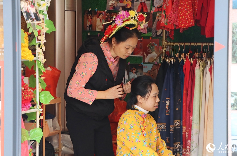 泉州府文庙附近，一名店主正为过路游客梳理头发以佩戴“簪花围”。人民网 黄东仪摄
