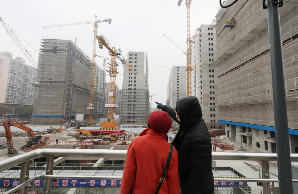 1月10日，两位市民在彭浦新村地铁站出站天桥上观看一建设工地。新华社记者 方喆 摄