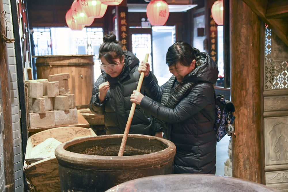 游客在平遥古城东湖老醋坊内体验陈醋发酵打耙（2022年1月28日摄）。新华社发（梁生仁摄）