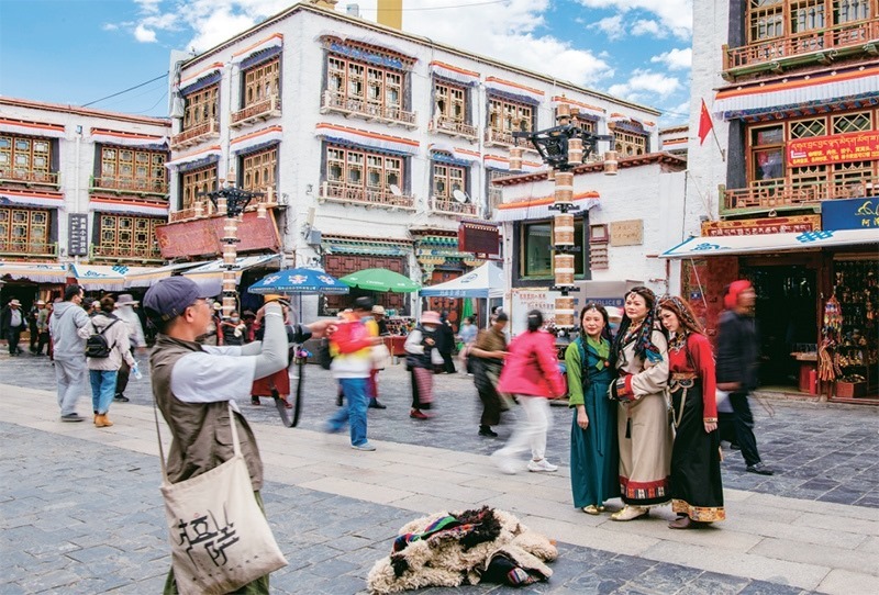 千年八廓街,见证民族团结。2021年7月,习近平总书记来到位于西藏拉萨老城区的八廓街,感慨地说:“千年八廓街,是我们各民族建起来的八廓街。各民族文化在这里交流交往交融,我们中华民族的大家庭在这里其乐融融。”图为2023年6月13日,游客身着藏装在八廓街拍照留念。 新华社记者 姜帆/摄