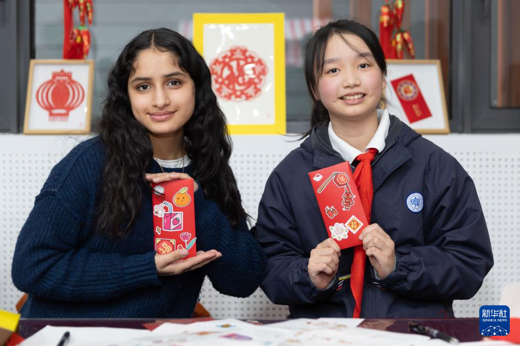 1月28日，美国马斯卡廷中学学生（左）和复旦大学第二附属学校学生展示互相送出的写有寄语祝福的红包。 新华社记者 王翔 摄