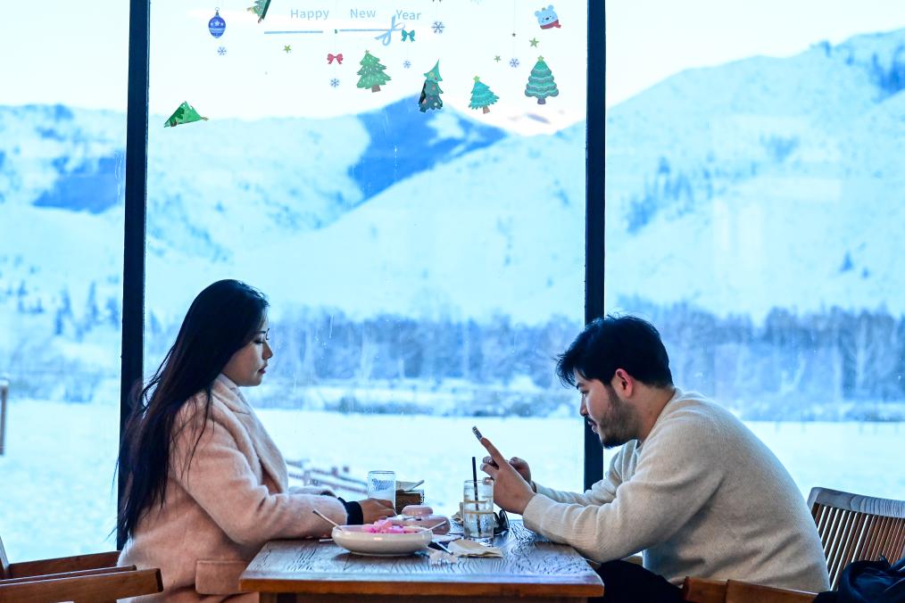 在新疆阿勒泰地区富蕴县可可托海镇塔拉特村，游客在一家咖啡厅内休憩（2023年12月22日摄）。新华社记者 丁磊 摄