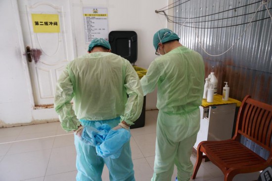 2015年4月23日，在塞拉利昂首都弗里敦，中国援塞医疗队医护人员完成当天救治任务走出隔离区时，已浑身湿透。