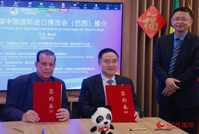 巴西外贸商会联合会会长阿代尔·罗伯托（左）与中国国际进口博览局副局长吴政平（中）现场签订协议。人民网记者 宋亦然摄