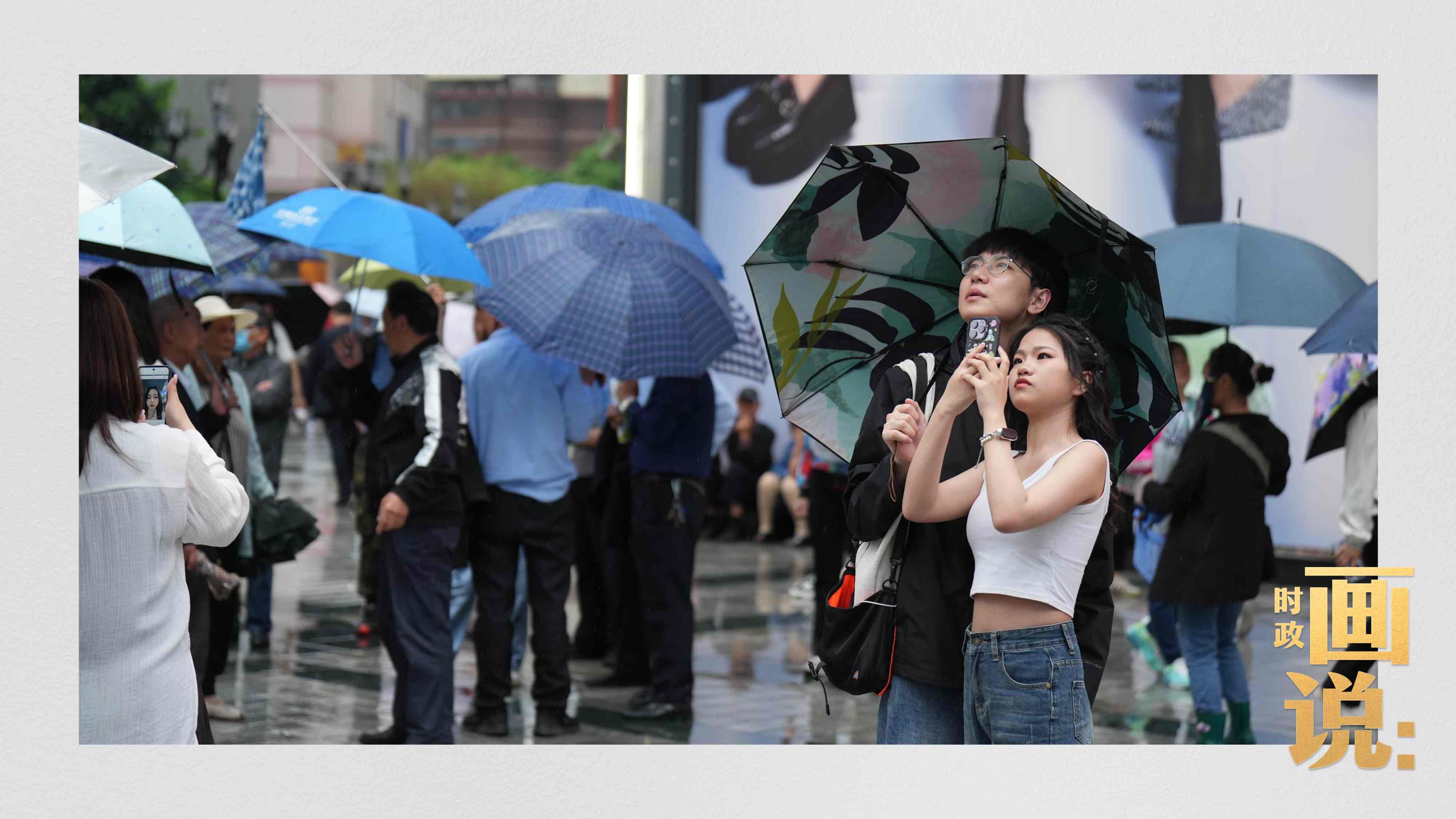 △细雨中的解放碑步行街，骑在父亲肩膀的小女孩好奇张望。