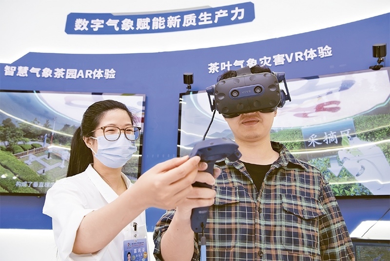 2024年5月23日，第七届数字中国建设峰会现场体验区在福州海峡国际会展中心向专业观众开放。本次现场体验区围绕本届峰会主题“释放数据要素价值，发展新质生产力”，设置“数字惠民”、“数字能力”、“数字基础”、“数字生态”、“数字赋能”五大板块。图为一名观众（右）在数字气象赋能新质生产力展台上进行体验。 新华社记者 魏培全/摄