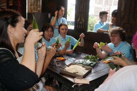 6月9日，美国青年代表在重庆永川松溉古镇体验包粽子。新华社记者 周思宇 摄