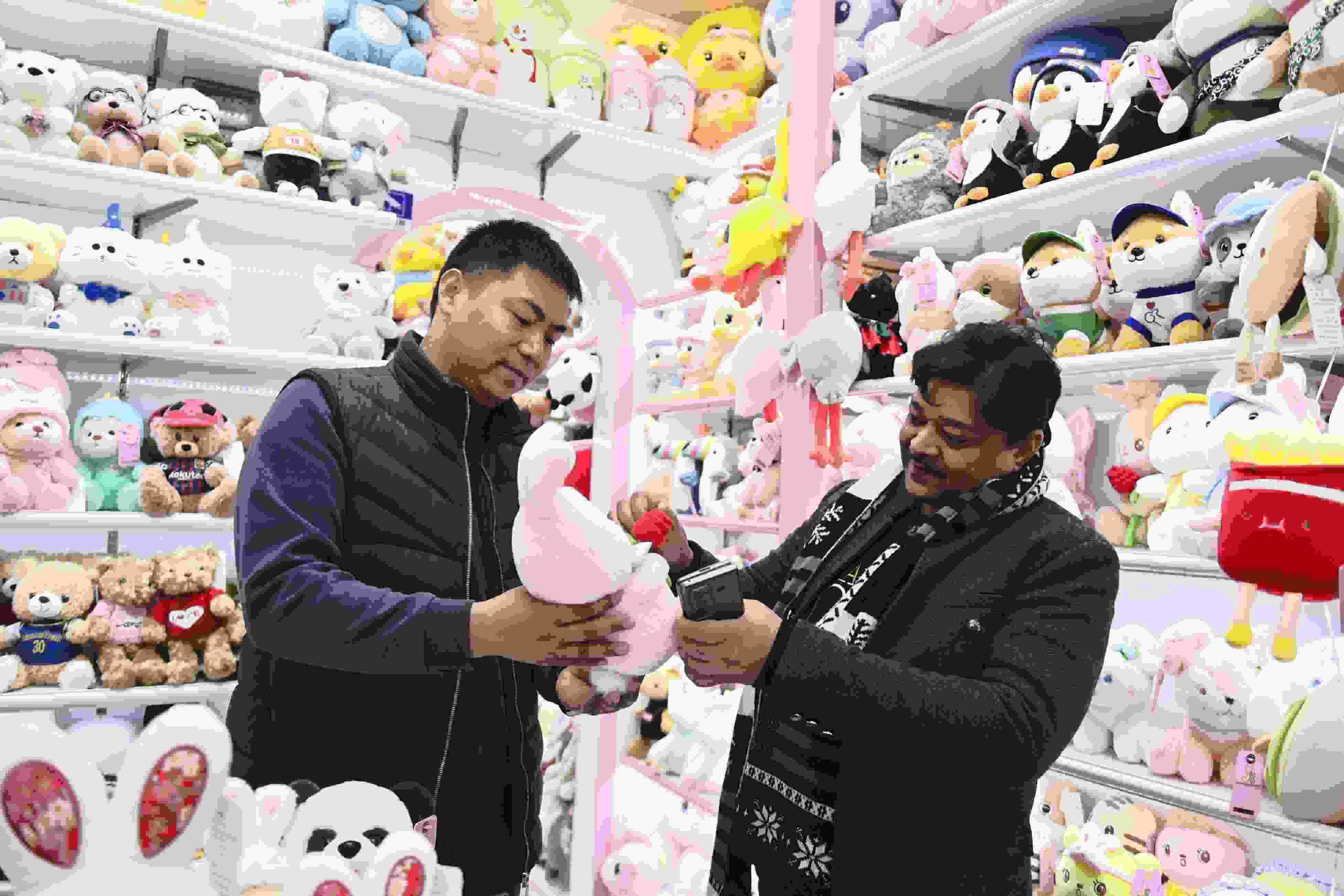 △ 2023年2月2日，来自印度的客商（右）在义乌国际商贸城的一家玩具店铺内选购。