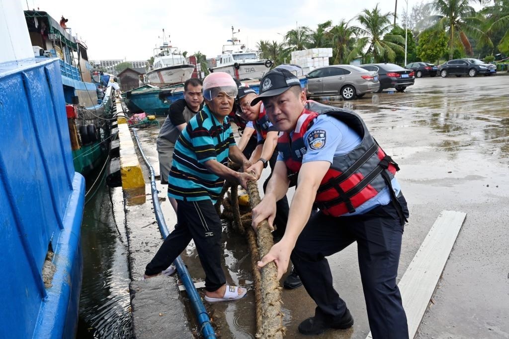 4日下午,海南省琼海市潭门海岸派出所民警帮助辖区群众加固回港渔船缆绳。(新华社发 吴凡 摄)