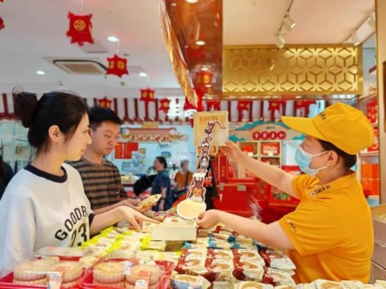 北京稻香村一家门店内，售货员向顾客展示新上市的月饼礼盒。（受访者供图）