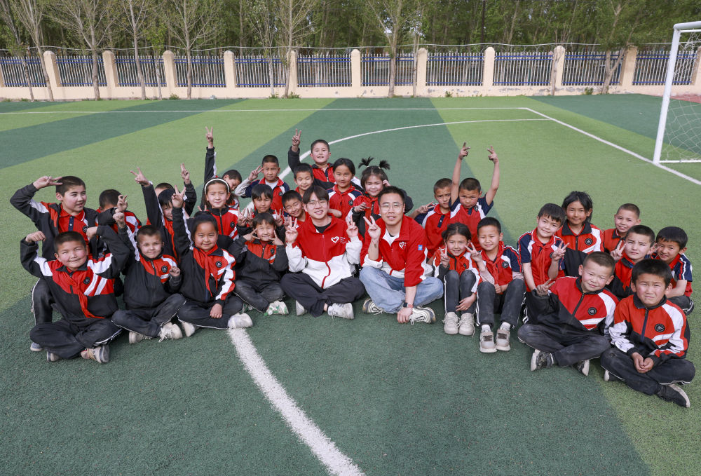 4月23日，在新疆克州阿图什市哈拉峻乡谢依特小学，支教教师王俊文（中左）、李轲凡（中右）和学生在一起。