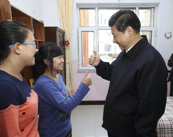 2014年1月28日，习近平总书记在内蒙古呼和浩特市儿童福利院宿舍向聋哑女孩王雅妮（左二）和放假“回家”的大学生闫志净学习哑语“谢谢”。