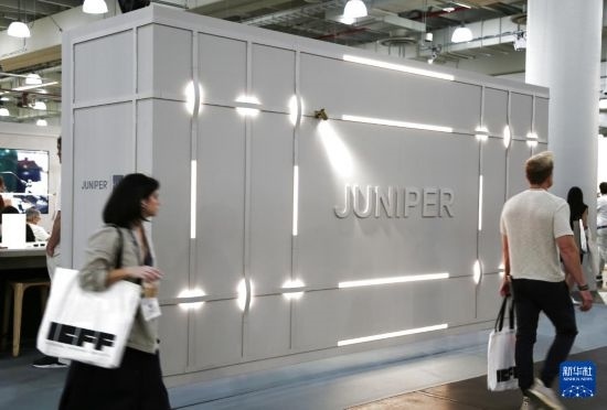 5月18日，在美国纽约举行的2025年国际当代家具展现场，参展人员走过美国灯饰设计和制造企业朱尼珀设计集团公司的展区。新华社记者 刘亚南 摄